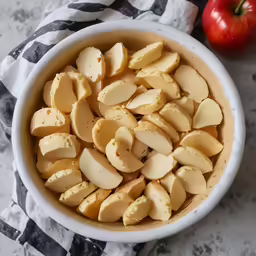 a bowl full of sliced apples on top of a towel