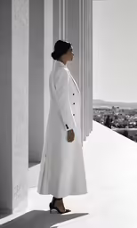 a woman in white standing on the side of a building
