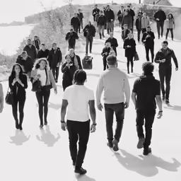 large crowd walking on sidewalk in winter, black and white photo
