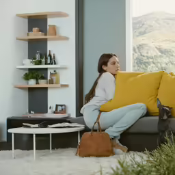 the woman is sitting on a couch and holding the purse