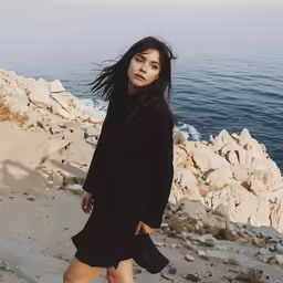 woman standing on rocky beach next to sea
