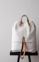 the large tote bag with leather straps is sitting on a stool