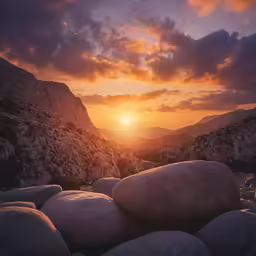some rocks are near a large mountain under the sun