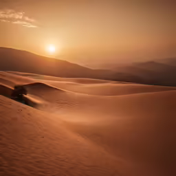 sun rising over a sandy landscape with rolling hills