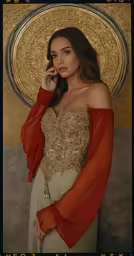 a woman poses in front of an ornate background wearing an off the shoulder dress