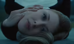 a woman laying on the ground with her face behind her head