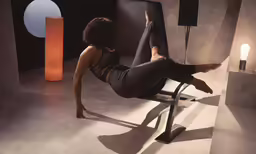 a woman does an aerial yoga move on a chair