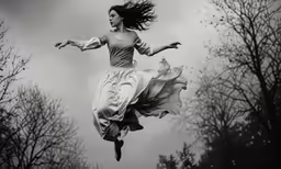 a woman in a flowing dress flying through the air