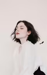 a woman with black hair posing in white shirt