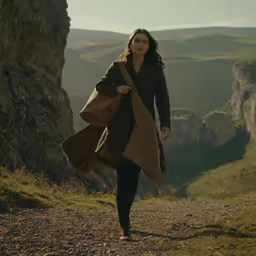 a beautiful woman walking on top of a dirt road