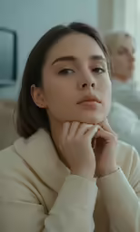 the young woman is sitting in front of a man on a couch