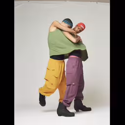 two men wearing different outfits hugging each other,two people hug each other while holding their hands in one of their arms