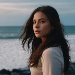 a beautiful young woman standing by the ocean
