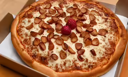 a small pizza in the cardboard box with a raspberry on top