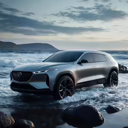 an suv is driving through the water next to rocks and ocean