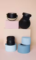 three colorful vases with black lids stand on the back of an object