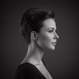 a woman with short black hair standing in a black background