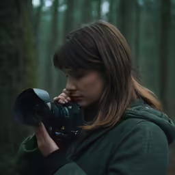 a woman is holding a camera with one hand and looking through it