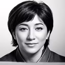 a woman wearing a collared shirt and tie smiling at the camera