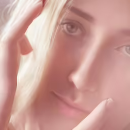 a woman with blonde hair, holding her hand to her face