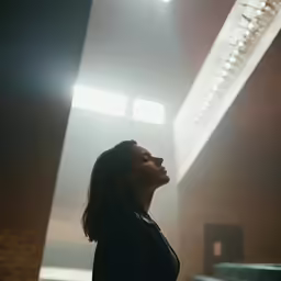 a woman standing in a large room with beams of light