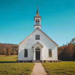 a white church with a steeple sitting in the middle of a field
