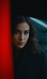 woman in suit looking out window at light