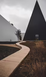 two building in different shapes are on a sidewalk