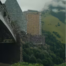 the buildings below the bridge are surrounded by green trees
