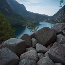 some rocks water and mountains under a cloudy sky