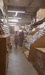 a man and woman are standing in a warehouse with shelves