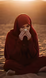 the woman with the red shawl is sitting in a desert