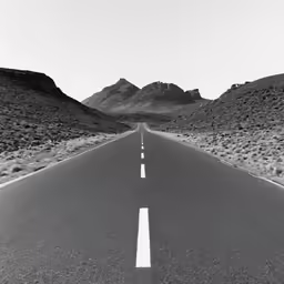 a black and white road stretches out into the distance