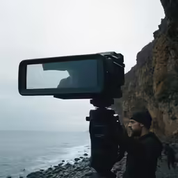 a man is on the beach making video