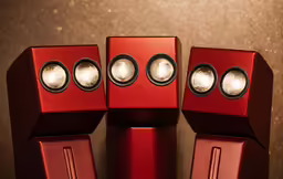 three red speakers with their lights on in front of a dark background