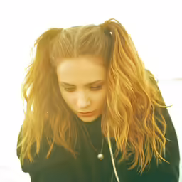 a girl is standing outside in her jacket looking at her cellphone