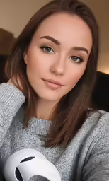 a girl with blue eyes holding a grey and white object