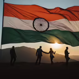 people holding an indian flag on top of a hill