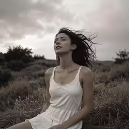 a woman in white sitting in the grass