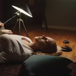 a woman laying down on the floor with her head down and a light on top of it