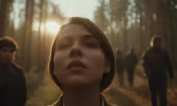several people walking in the woods at sunset
