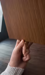 hand hiding between a wooden panel with other hand