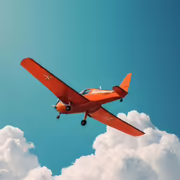 an orange airplane flying above a blue sky with puffy clouds