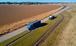 two trucks traveling down a country road in the middle of nowhere,two trucks traveling down the highway in front of some sand dunes