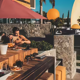 people eat food out on a wooden table with some umbrellas