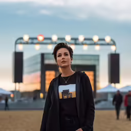 a woman poses in front of a stage with tents