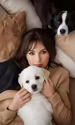 a woman laying down holding a white and black dog