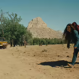 the truck is coming down the road while a woman walks towards it