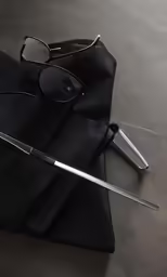a knife and pair of sunglasses on top of black pants