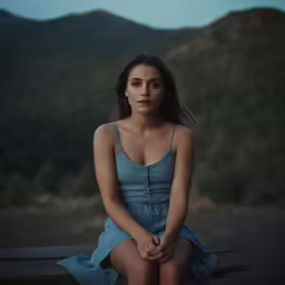 a woman in a dress is sitting on a bench